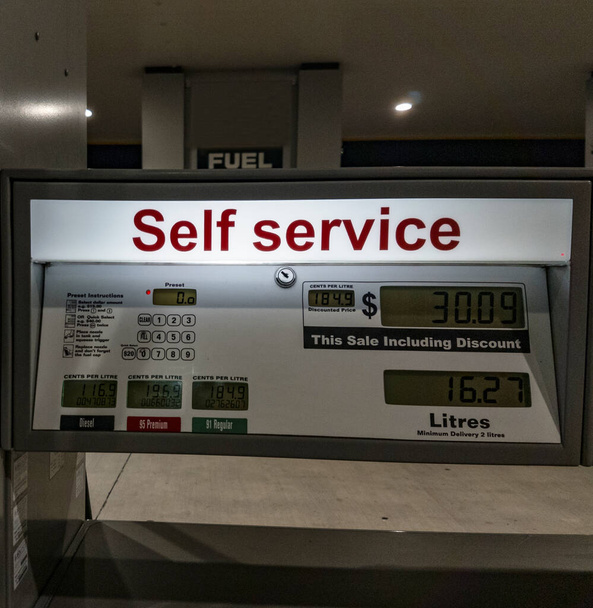 Podświetlany znak samoobsługowy na stacji benzynowej przed szafką pompy. - Zdjęcie, obraz
