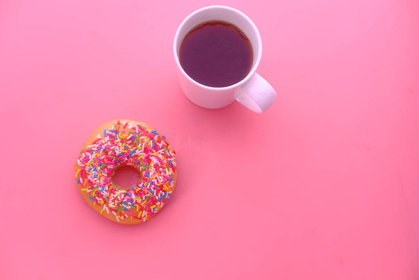 Xícara de café e donuts em um fundo rosa
. - Foto, Imagem
