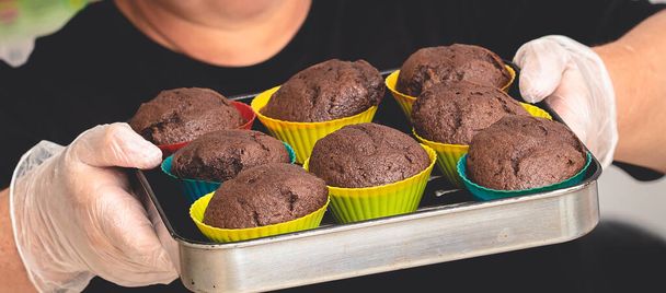  woman is holding chocolate muffins in a tray - Foto, Bild