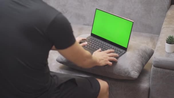 Homem 4K trabalhando no laptop de computador de tela verde, sente-se ao lado do sofá da sala de estar, homem asiático de camisa preta trabalhando durante a epidemia do vírus da corona covid-19, freelancer, fique em quarentena de trabalho em casa
 - Filmagem, Vídeo