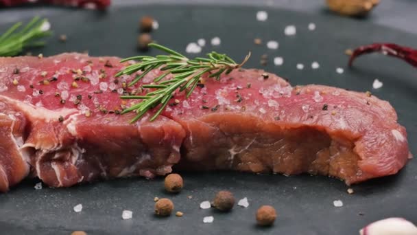 Beef sirloin raw steaks with spices on a dark table. - Footage, Video
