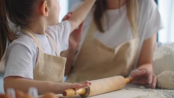 Daughter and mother at home in the kitchen in aprons indulge and have fun give five and sprinkle with flour - Imágenes, Vídeo