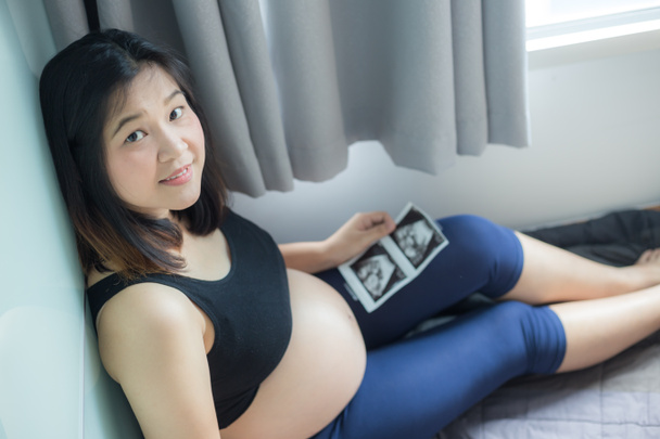 Happy pregnant healthy women sitting in cozy room looking kid photo, New born concept - Foto, immagini