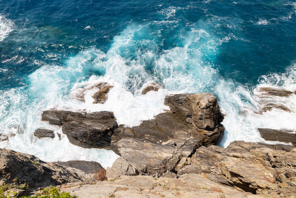 Las grandes olas azules del mar hacen espuma blanca y se estrellan en el acantilado de la costa de la roca
 - Foto, Imagen