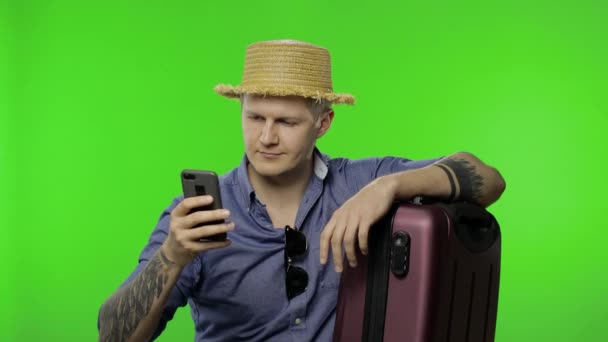 Portret turysty z walizką przy użyciu telefonu komórkowego, czat. Klucz chromowy - Materiał filmowy, wideo