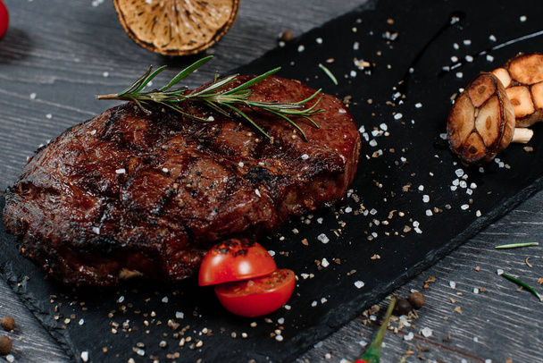 huge juicy steak meat on black plate on grey served table. traditional dish menu served in a restaurant - 写真・画像
