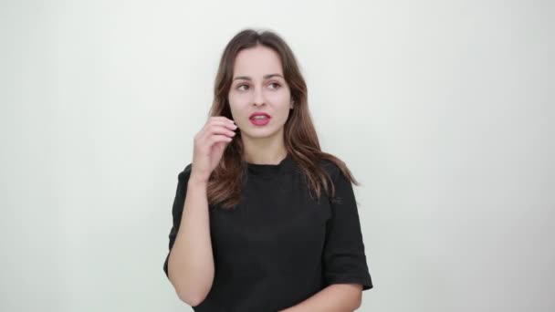 Söpö nuori brunette nainen musta t-paita hämmentynyt tyttö puree kynsiään
 - Materiaali, video