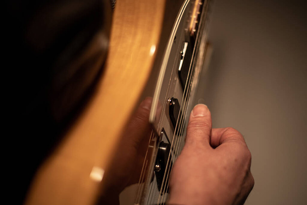 Человек, держащий в руках гитару и играющий на ней
 - Фото, изображение