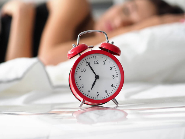 Rode ouderwetse wekker ingesteld op zeven uur in de ochtend - Foto, afbeelding