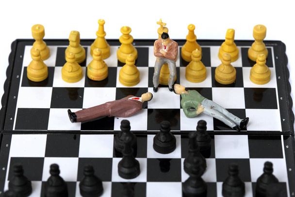 Model biznesmena na szachownicy. - Zdjęcie, obraz