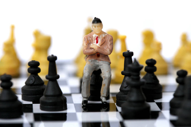 Model biznesmena na szachownicy. - Zdjęcie, obraz