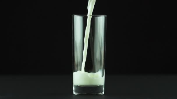 Melk gieten in glas close-up geïsoleerd op zwarte achtergrond Slow motion - Video