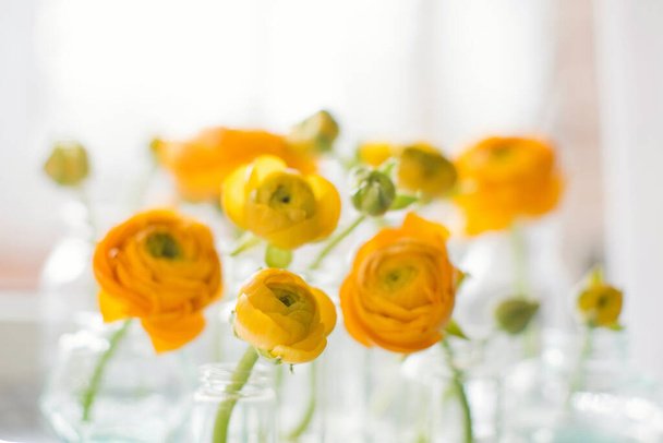 Beautiful orange ranunculus flowers in vintage bottles and vases standing on a vintage silver tray. Small bouquets or gifts - Foto, immagini