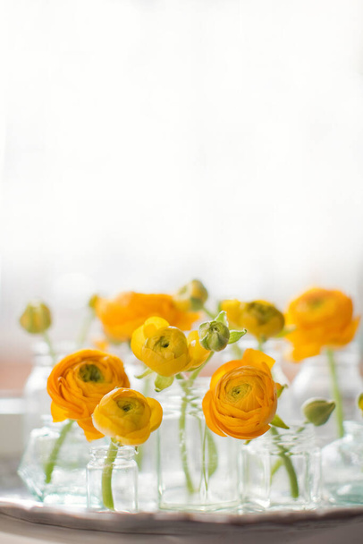 Prachtige oranje ranunculus bloemen in vintage flesjes en vazen op een vintage zilveren dienblad. Kleine boeketten of geschenken - Foto, afbeelding