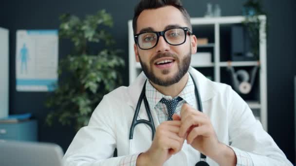 Portrait of attractive guy in medical uniform talking and gesturing recommending drugs in clinic - Filmagem, Vídeo