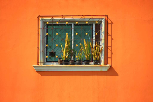 Minimalistisches Foto eines Fensters an einer orangefarbenen Wand - Foto, Bild