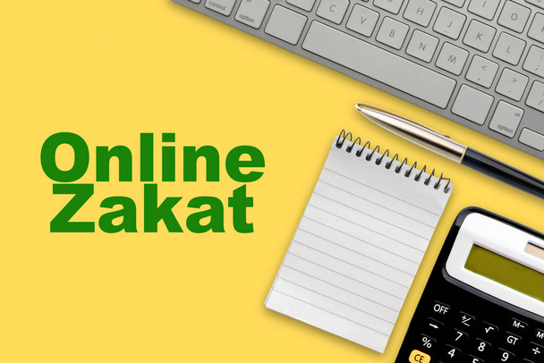ONLINE ZAKAT (islamische Steuer) Text mit Notizblock, Taschenrechner, Tastatur und Füllfederhalter auf gelbem Hintergrund. Zakat (Islamische Steuer), Business und islamisches Konzept - Foto, Bild