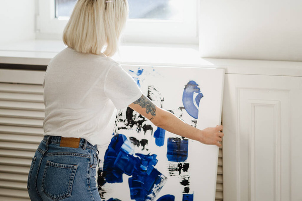 Junge Frau bringt abstrakte Farbe an die Wand - Foto, Bild