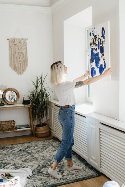 Jonge vrouw plaatst abstracte verf op de muur - Foto, afbeelding