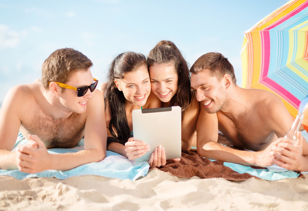 Group of smiling people with tablet pc on beach - 写真・画像