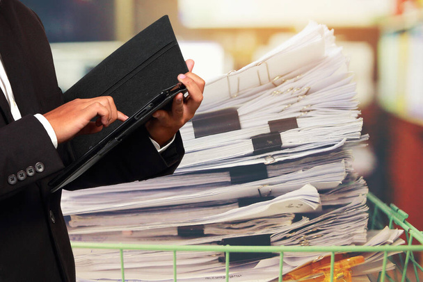 Businessman holding tablet in his hands and Paper documents stacked background. Concept the path to win success. - Photo, Image