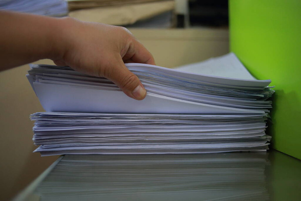 Pessoa que toma documentos empilhados no escritório moderno com fundo turvo
 - Foto, Imagem