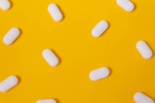 White pills on fun bright yellow background. Big vitamins and supplements for energy. Healthcare concept. Top view. Open composition. - Foto, Bild