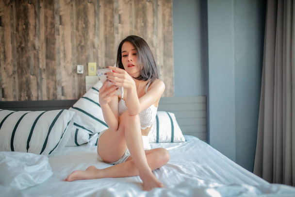 Indoor portrait of beautiful happy woman waking up in her room, she is stretching and smiling. - Foto, afbeelding