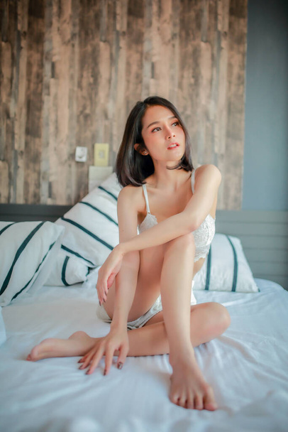 Indoor portrait of beautiful happy woman waking up in her room, she is stretching and smiling. - 写真・画像