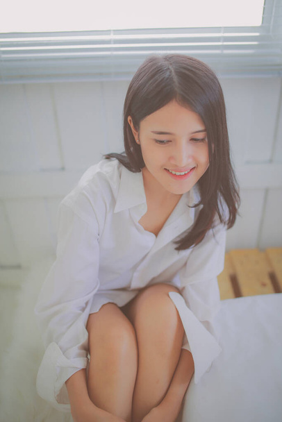 hermosa joven asiático mujer sentado en blanco ropa de cama en suave mañana luz. - Foto, imagen