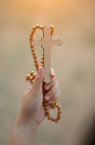 Close-up wooden cross in the hand with focus on the cross blessing from god on sunlight background, hope concept. - Photo, Image