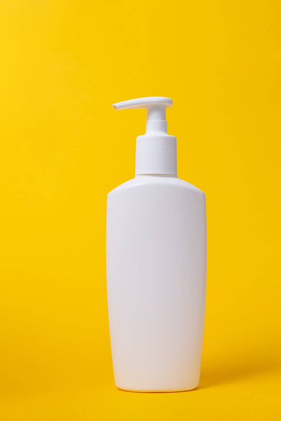 Close up. Mock-up white plastic bottle with dispenser on vivid yellow background. Beauty and self care concept. - Foto, Imagem