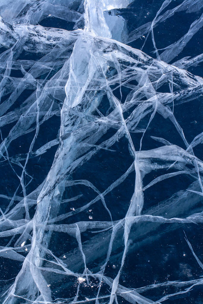 Small cracks in transparent clear ice. Natural texture of a winter lake. Vertical. - Photo, Image