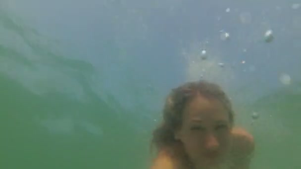 Denizde suyun altında bir kadın yüzüyor. Kız okyanusa dalıyor ve suyun altında yüzüyor.. - Video, Çekim