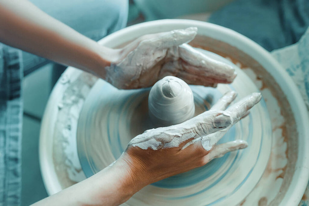 Крупный план женских рук, скульптур глины на колесе гончара. Концепция хобби и творчества дома и в мастерской студии
 - Фото, изображение