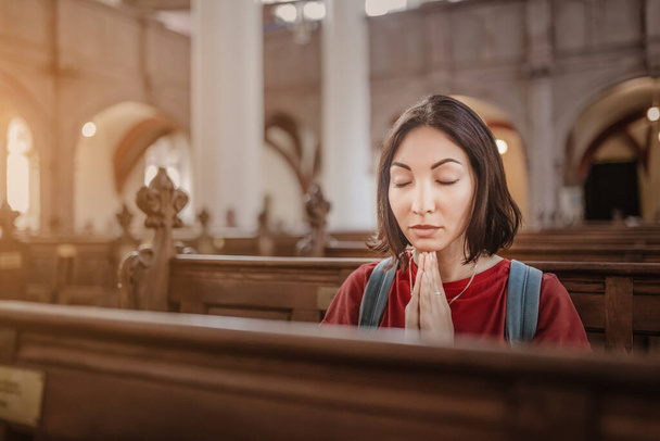 Mulher asiática rezando em um banco na igreja. Pedir ajuda e adoração conceito
 - Foto, Imagem