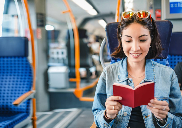 Happy asian girl traveler checks her visa in passport while traveling by railway train - Valokuva, kuva