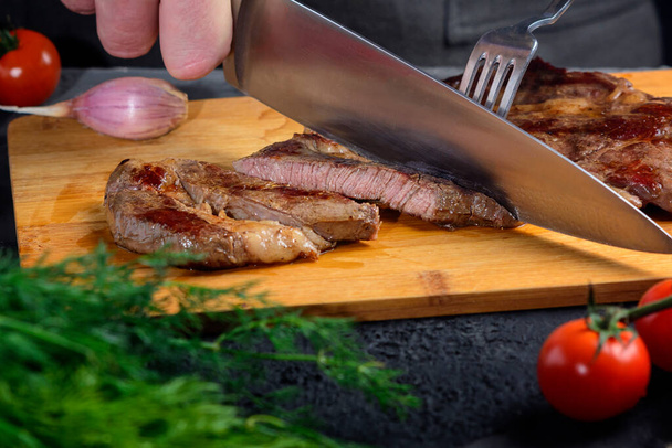 Свіжоприготований яловичий стейк нарізають скибочками. М'ясо середнього рідкісного
 - Фото, зображення