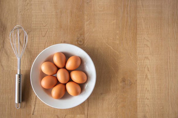 Huevos de pollo y batidor de huevos sobre fondo de madera
. - Foto, imagen