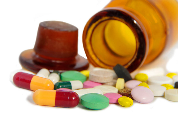 Medicamentos y pastillas. Medicamentos multicolores sobre fondo blanco de cerca. Frasco de vidrio marrón con pastillas
. - Foto, Imagen