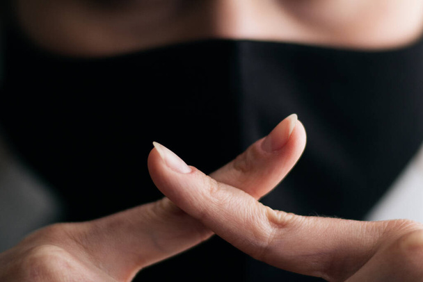 jovem mulher em uma máscara protetora preta mostrando um gesto de silêncio com dois dedos cruzados na boca, conceito de silêncio da verdade, privacidade da informação, conspiração, traição da informação
 - Foto, Imagem