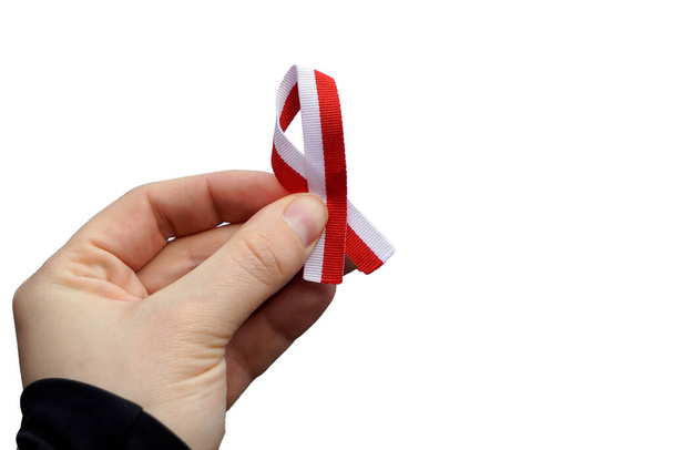 Hand with red and white ribbon on white background, isolated. Flag background national holiday country november celebration.1 of May, flag or independence or labor day. Government holiday in poland. - Photo, image