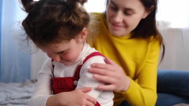 Worrying loving mother sitting on bed near upset little daughter, saying sorry. Young mom consoling sad preschool girl after quarrel, parent and child empathy, compassion. Family problems concept. - Metraje, vídeo
