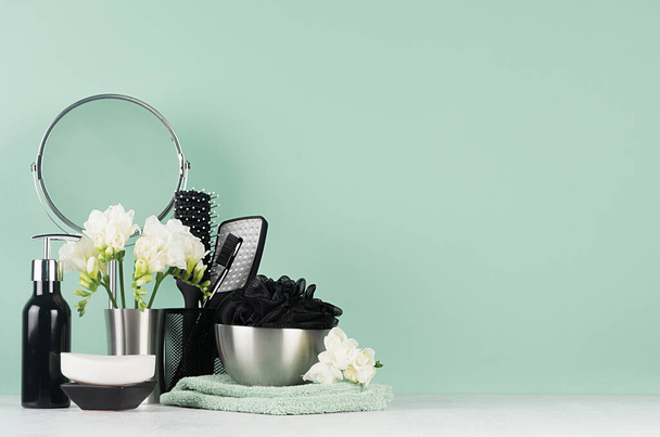 Mint menthe bathroom interior with bath cosmetic - black shower sponge, towel, mirror, white flowers, soap, dispenser, toothbrush, brush, on white wood. - Foto, Bild