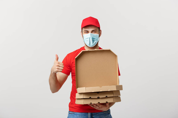 Pizza szállítási koncepció. Fiatal fiú pizzás dobozokat szállít és mutat be dobozokban. Fehér alapon elszigetelve - Fotó, kép