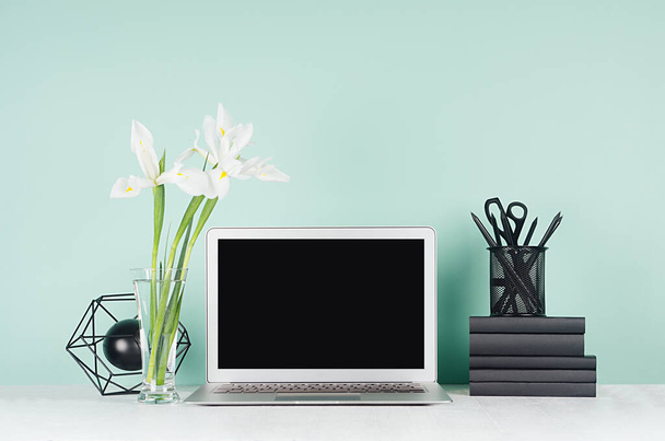 Spring workplace with blank notebook screen, black stationery, books, abstract atom model, white fresh flowers in elegant green mint menthe interior on white wood table. - Fotografie, Obrázek