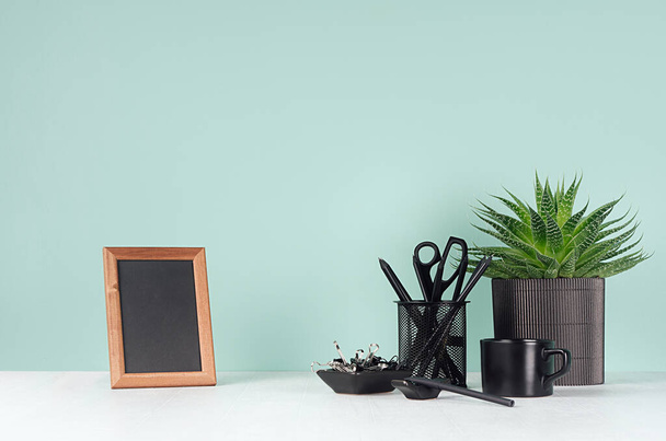 Fresh home workspace with black stationery, books, coffee cup,  aloe house plant, photo frame in elegant green mint menthe interior on white wood desk, copy space. - Photo, Image