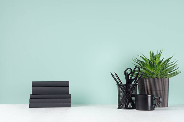 Fresh spring workplace for work and study with black stationery, books, coffee cup, aloe plant in light green mint menthe interior on white wood desk, copy space. - 写真・画像