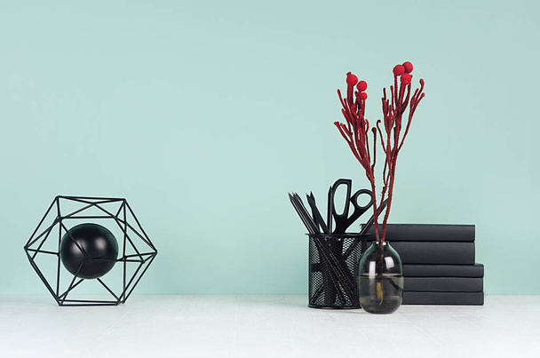 Light spring school workplace with black stationery, books, red branch in glass vase, decorative model atom on green mint menthe wall and white wood table, copy space. - Foto, Bild