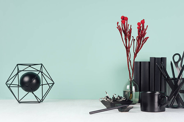 Elegant workplace with black stationery, books, red branch, abstract sculpture as model atom and coffee cup on green mint menthe wall and white wood table. - Fotografie, Obrázek